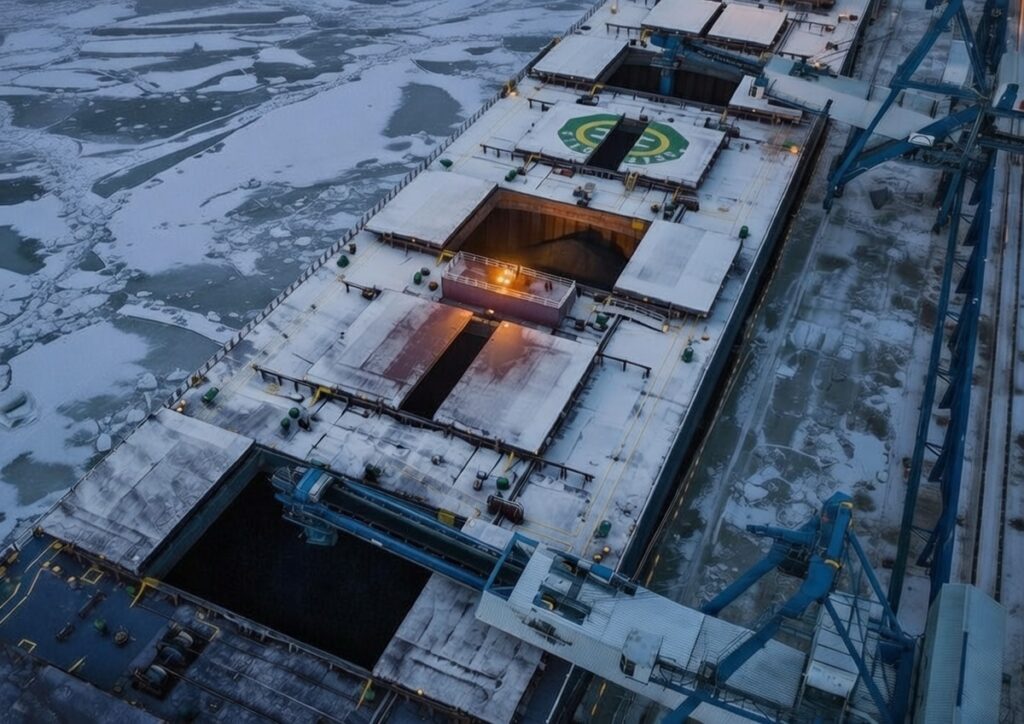 Ice-covered Baltic Sea port with frozen water and a coal ship at the dock under winter conditions.