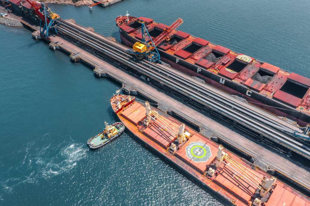 Coal loading operation at a bulk terminal with a coal barge and tug alongside