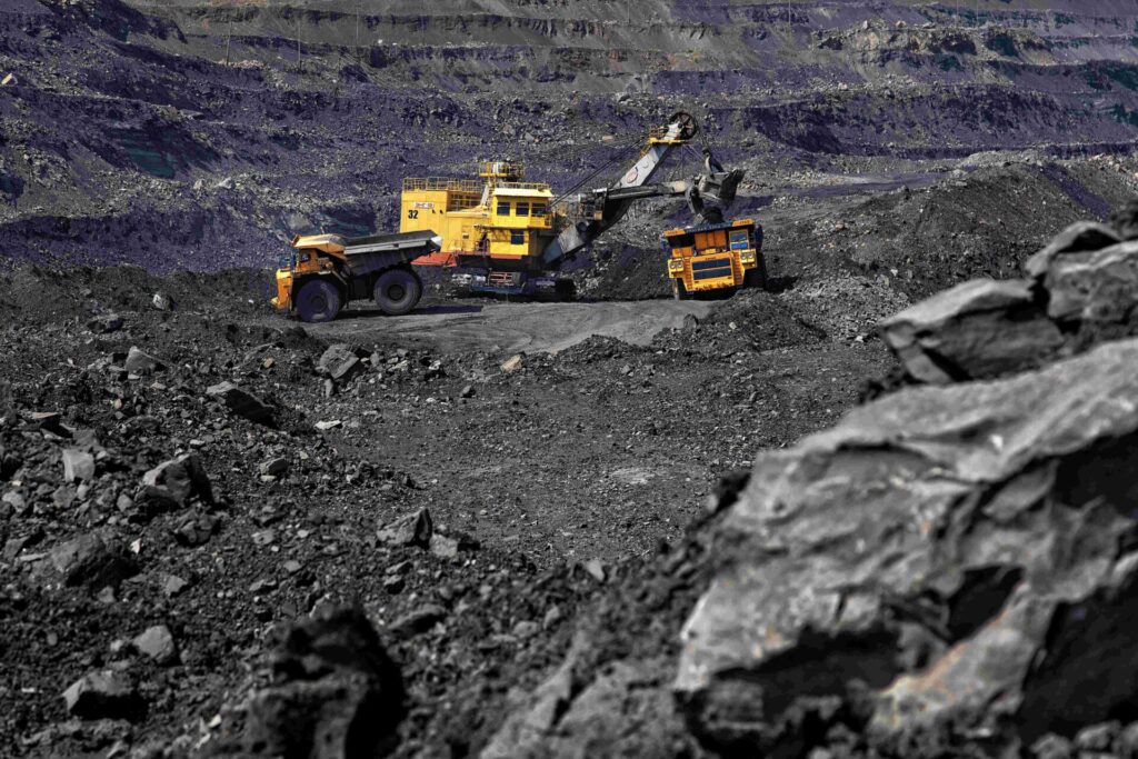 Open-pit coal mining operation in Kuzbass with excavator and haul trucks loading coal