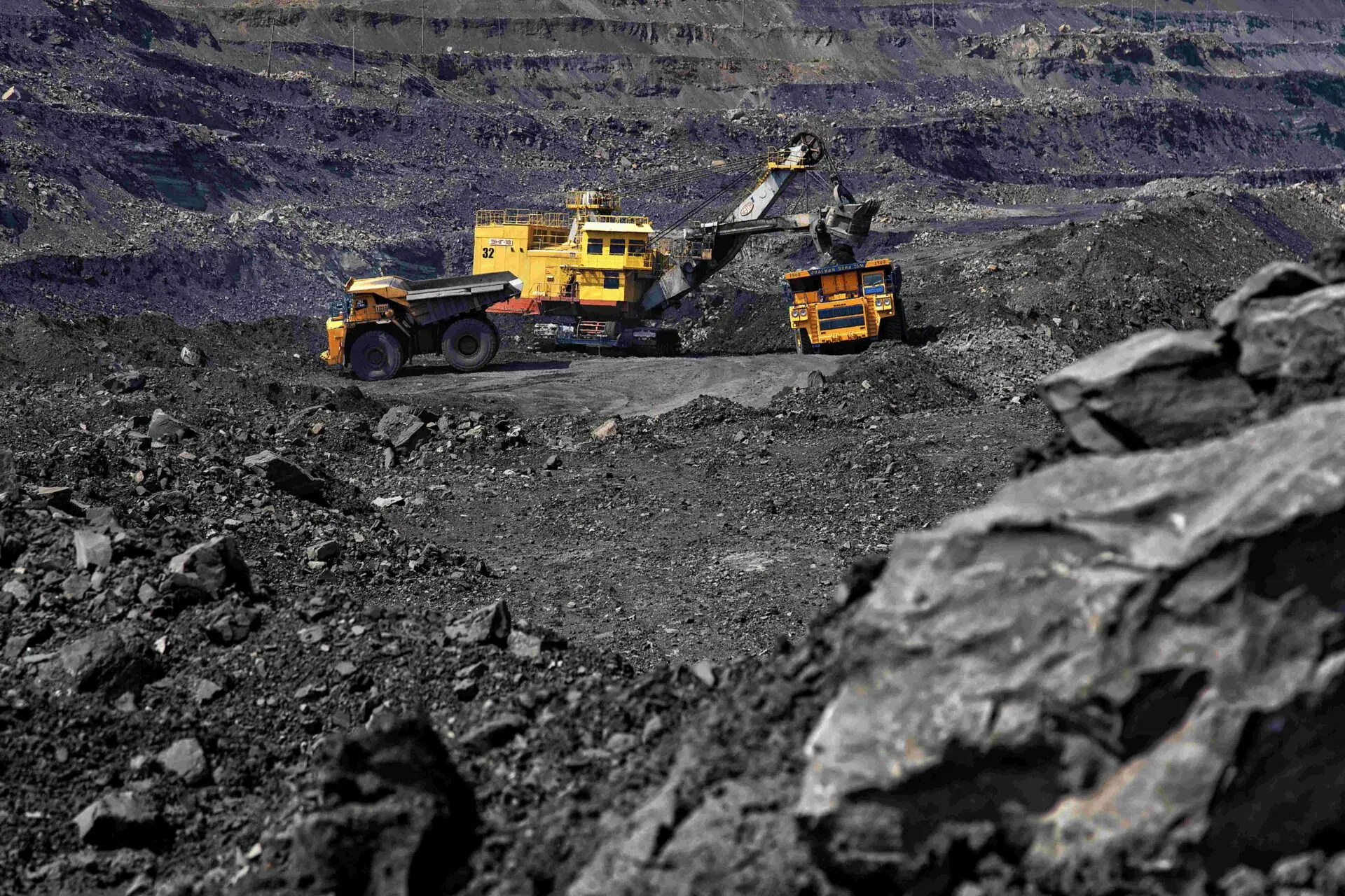 Open-pit coal mining operation in Kuzbass with excavator and haul trucks loading coal