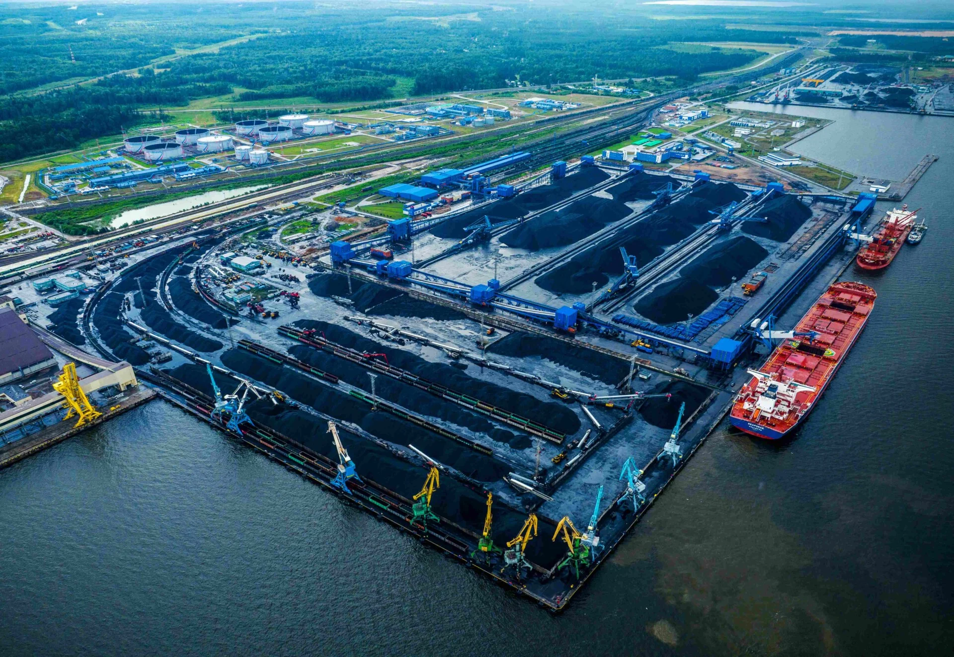 Aerial view of Ust-Luga port on the Gulf of Finland with coal stockpiles and loading infrastructure.