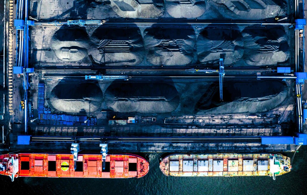 Aerial view of coal stockpiles and bulk carriers at a Russian port terminal.