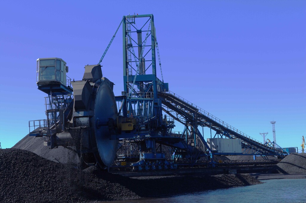 Coal handling machine loading and moving coal at an industrial coal terminal.