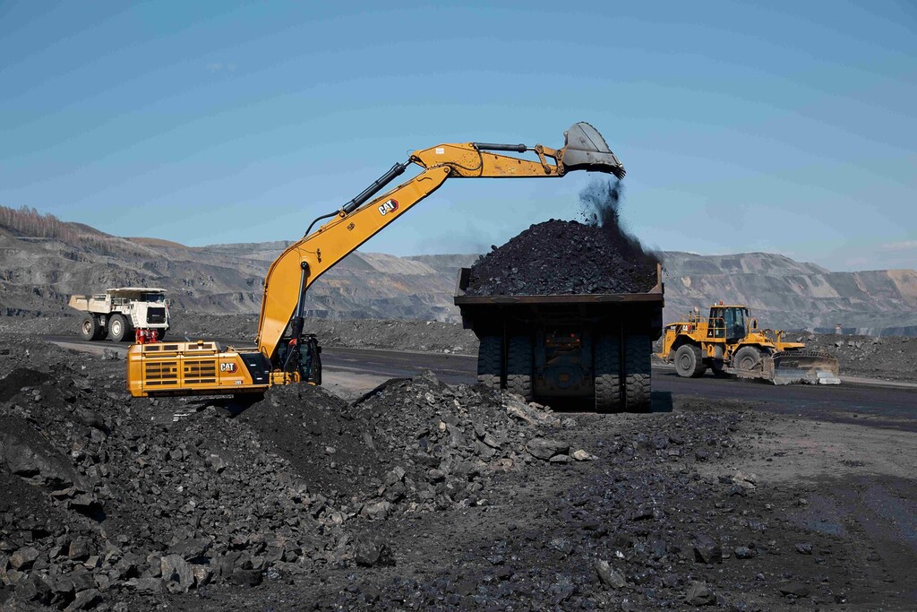Excavator loading coal into a haul truck at an open-pit coal mine.