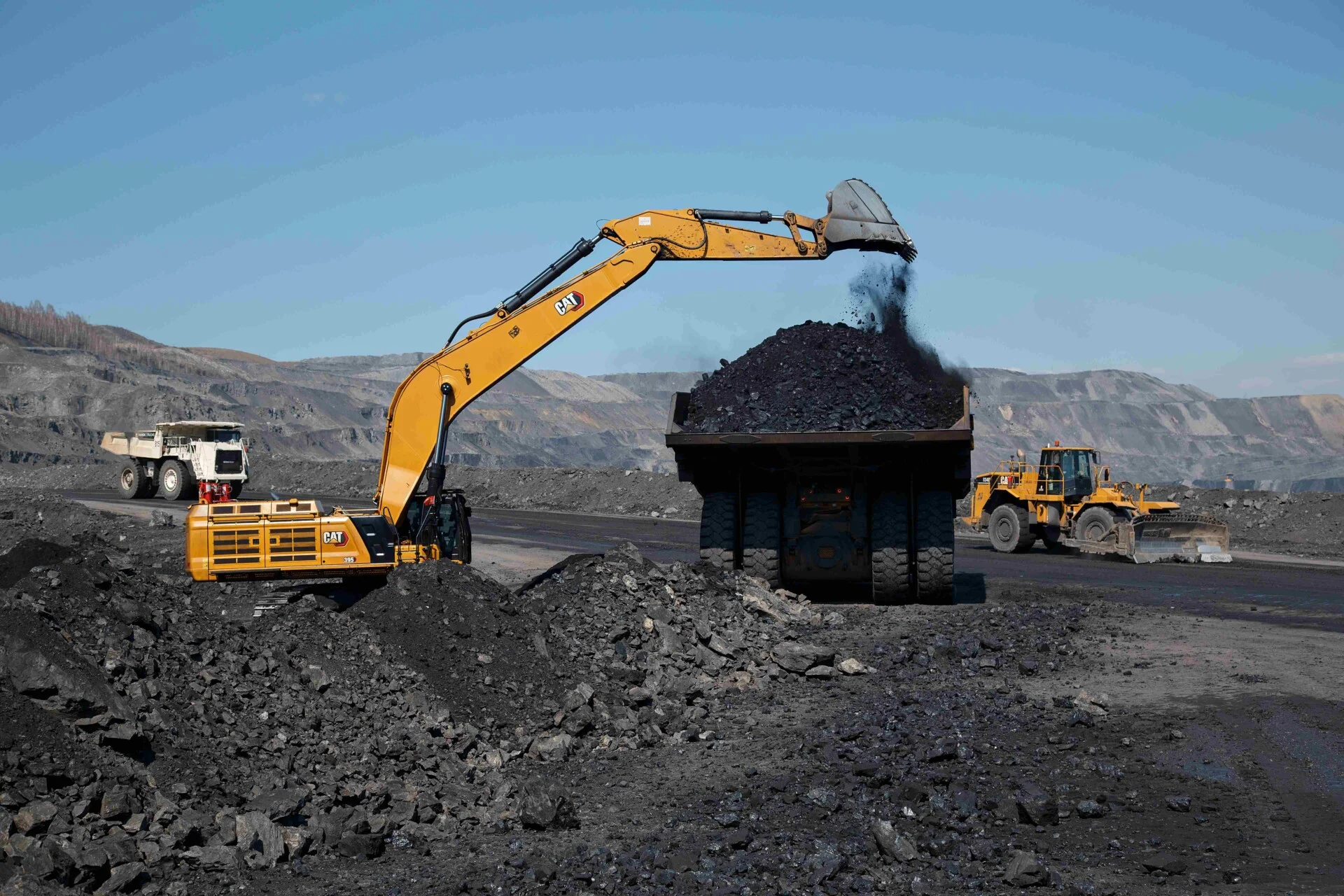 Excavator loading coal into a haul truck at an open-pit coal mine.