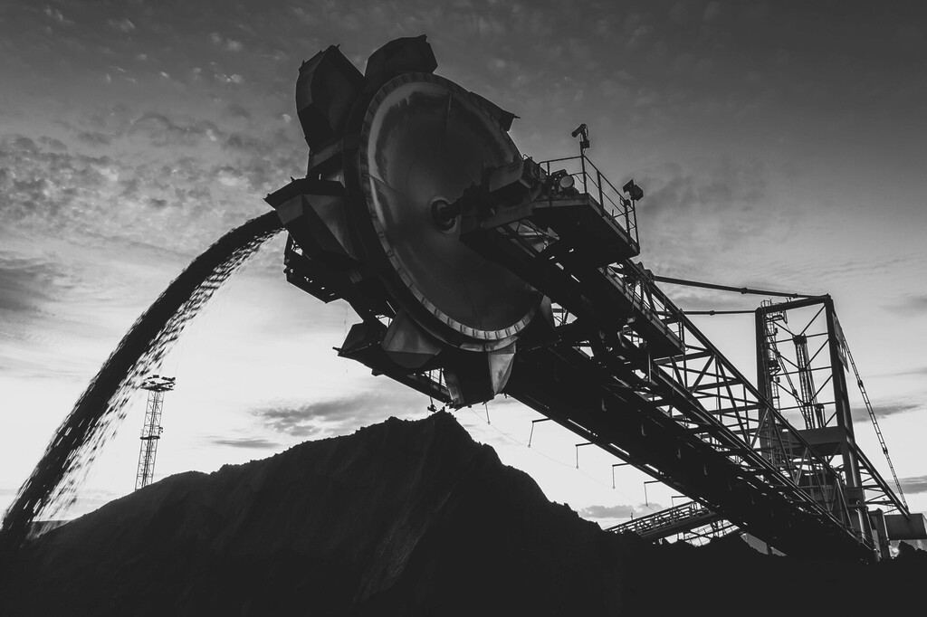 Black-and-white image of coal handling equipment loading coal onto a stockpile.
