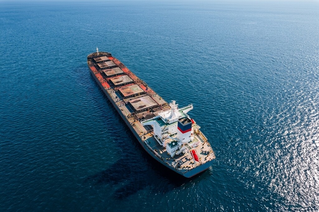 Bulk coal carrier sailing at sea with open cargo holds.