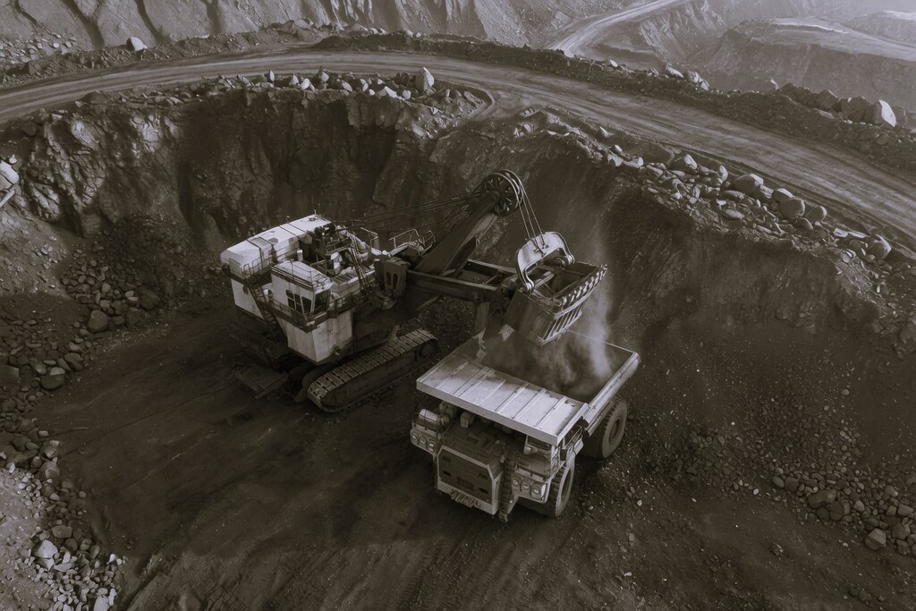Excavator loading coal into a haul truck at an open-pit Russian coal mine