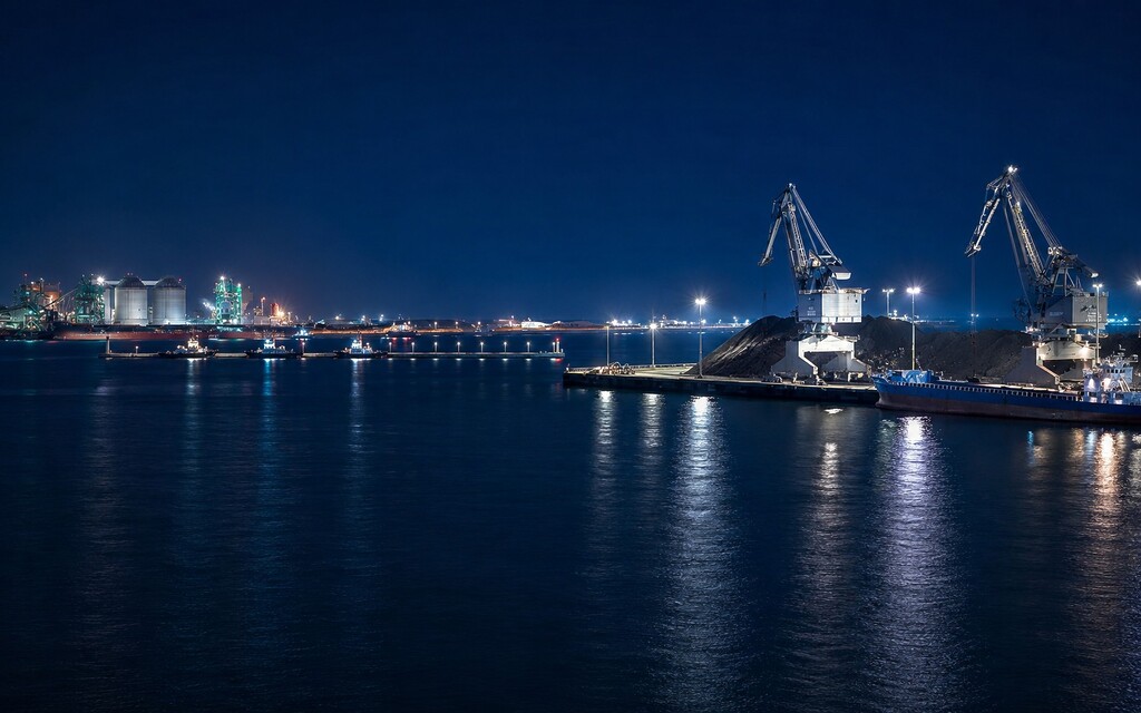 Night view of a coal terminal with cranes, stockpiles and ships at a South Korean port.