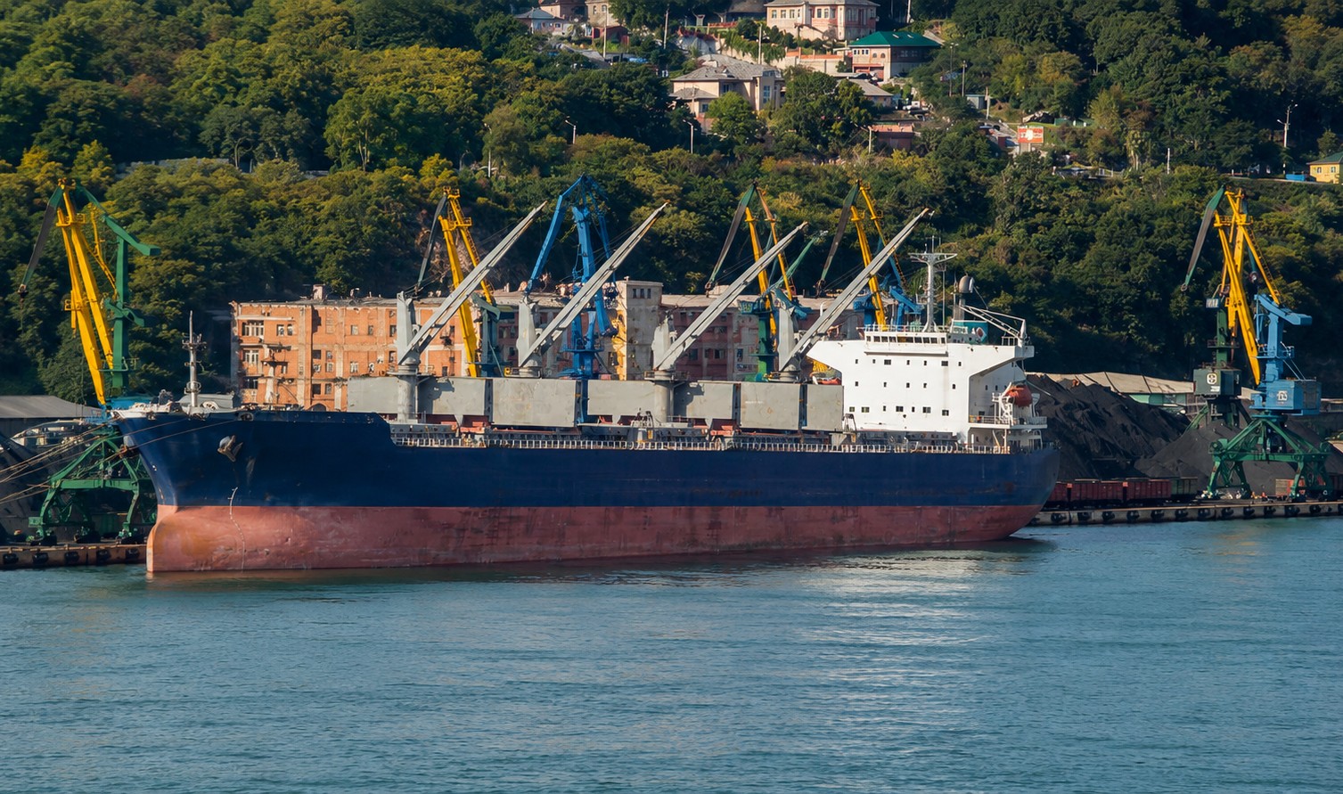 Bulk carrier being loaded with coal at a port near an urban area in the Russian Far East.