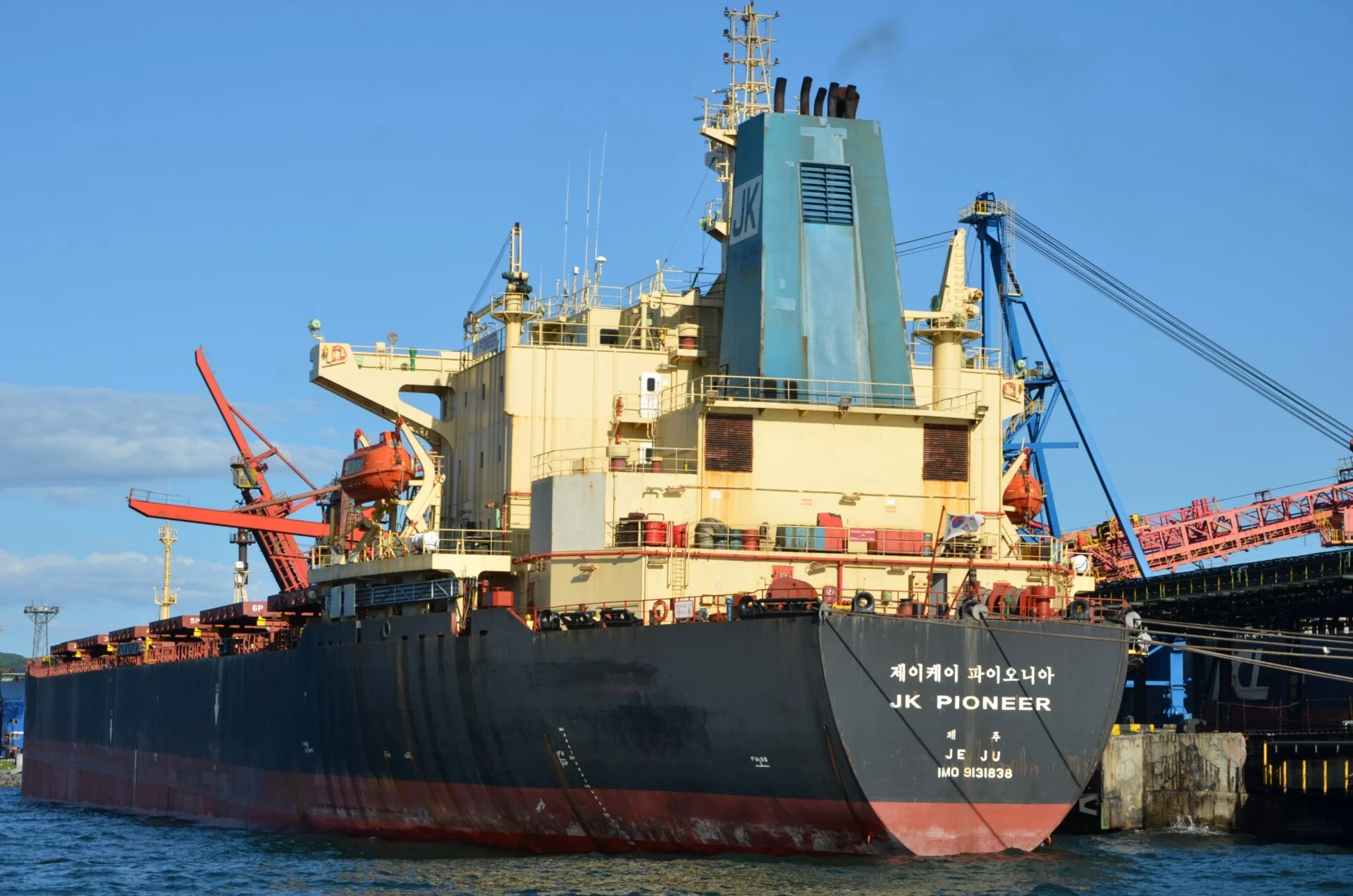 Bulk carrier docked at a South Korean coal terminal with loading equipment alongside.