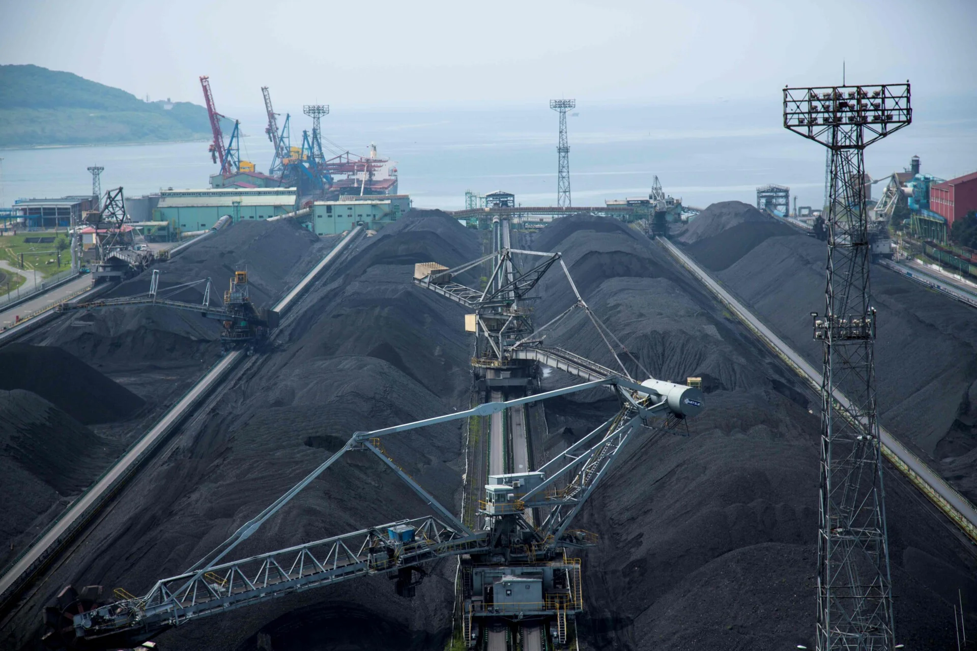 Coal stockpiles at export terminal | The Coal Hub Large coal stockpiles and handling equipment at an export terminal near the sea.
