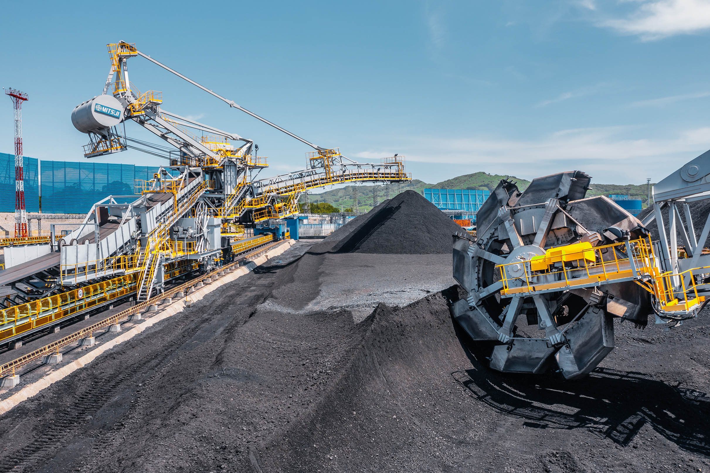 Large coal stockpiles with industrial conveyor and handling equipment at a coal terminal.