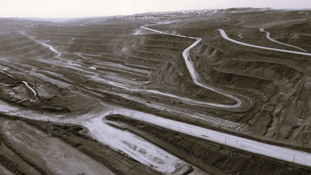 Large terraced open-pit coal mine with haul roads and mining activity across the site.
