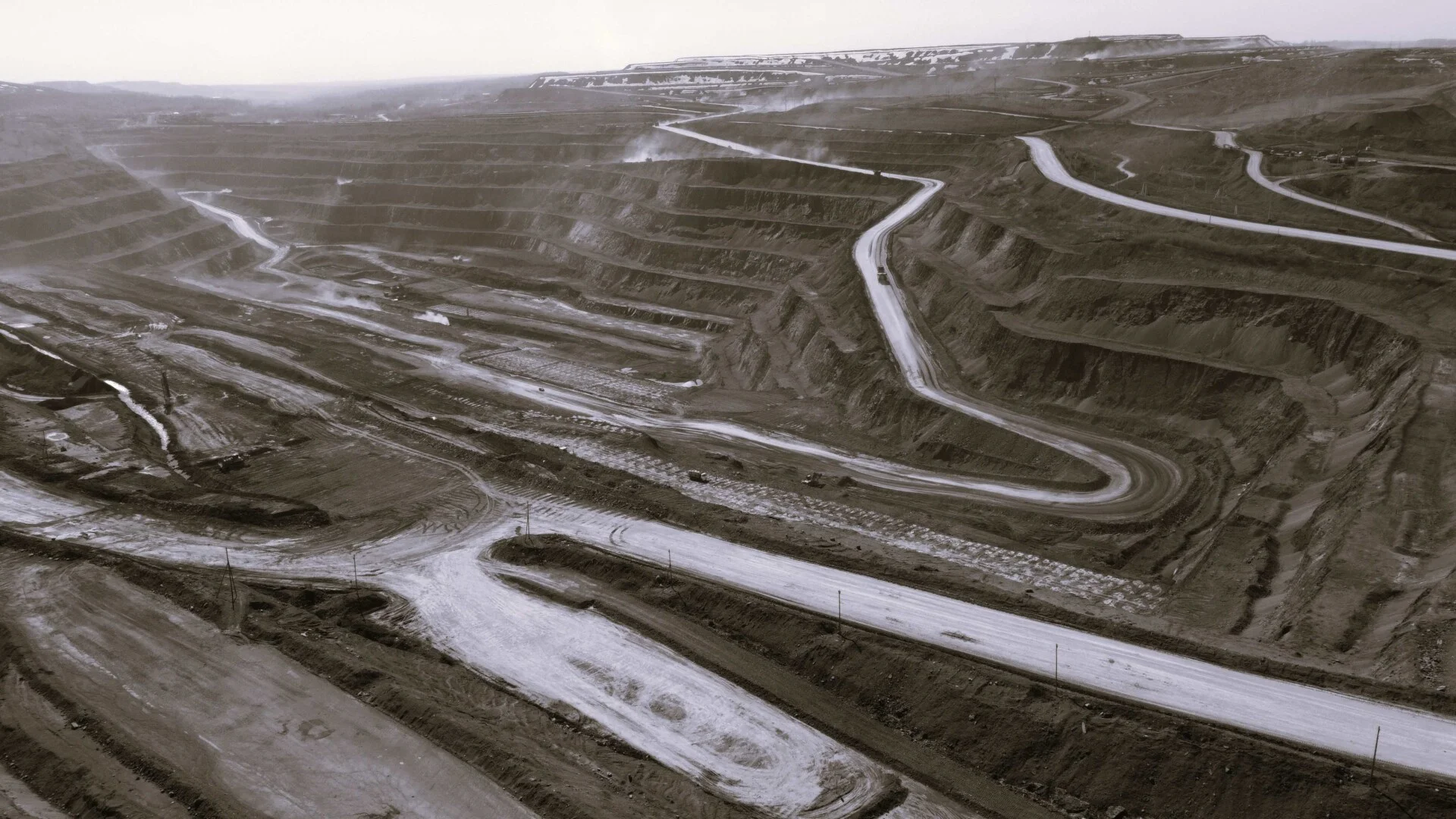 Large terraced open-pit coal mine with haul roads and mining activity across the site.