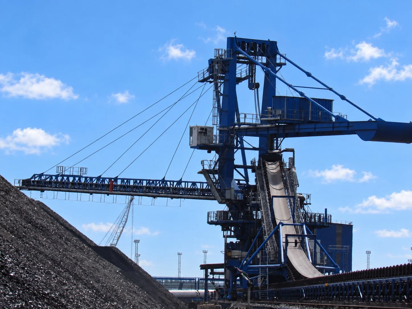 Large coal handling and conveyor equipment operating beside a coal stockpile at an export terminal.
