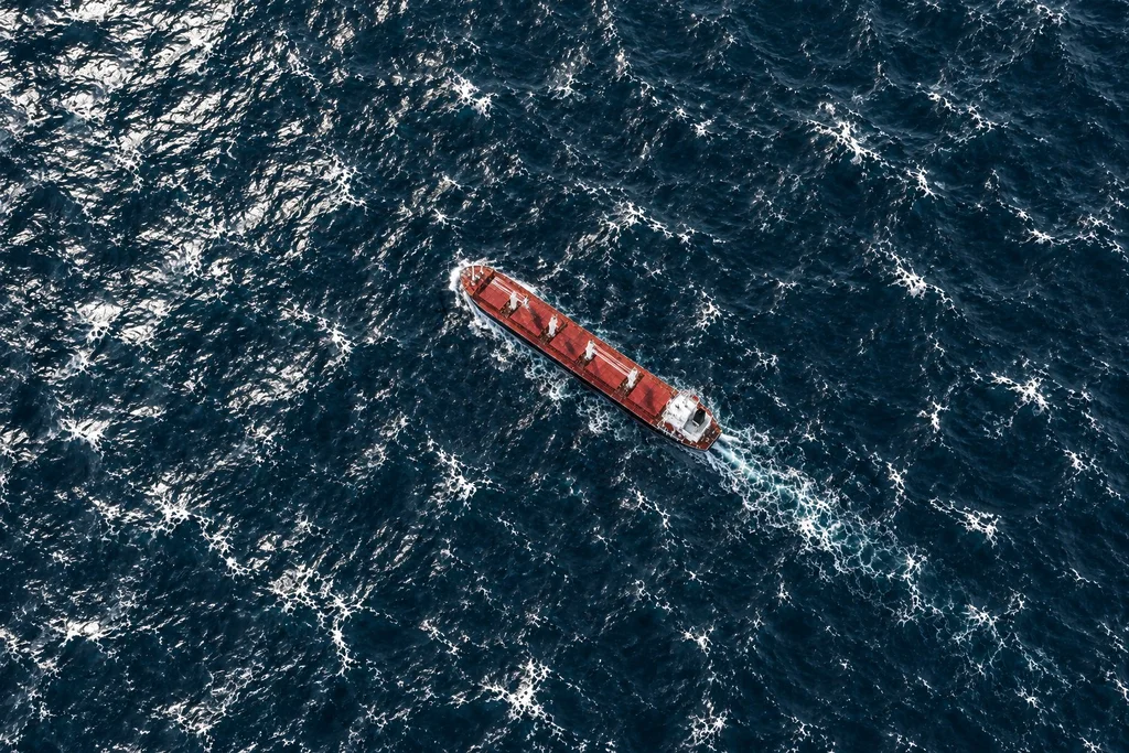 Aerial view of a bulk carrier sailing through open sea waters.