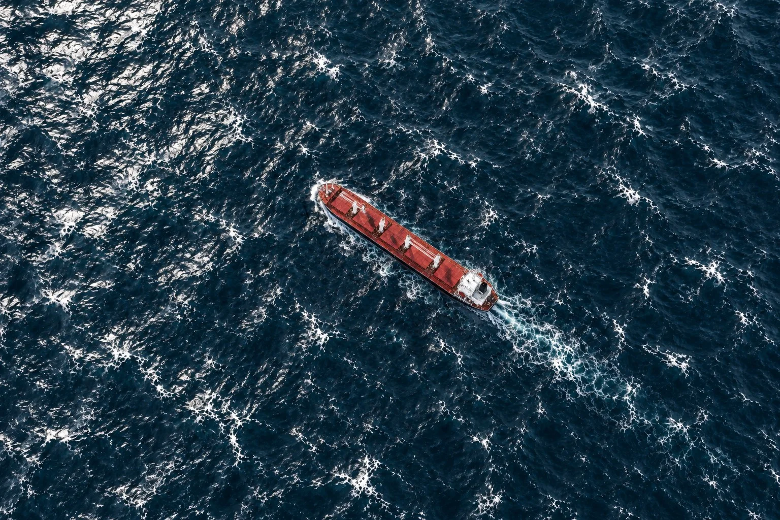 Aerial view of a bulk carrier sailing through open sea waters.